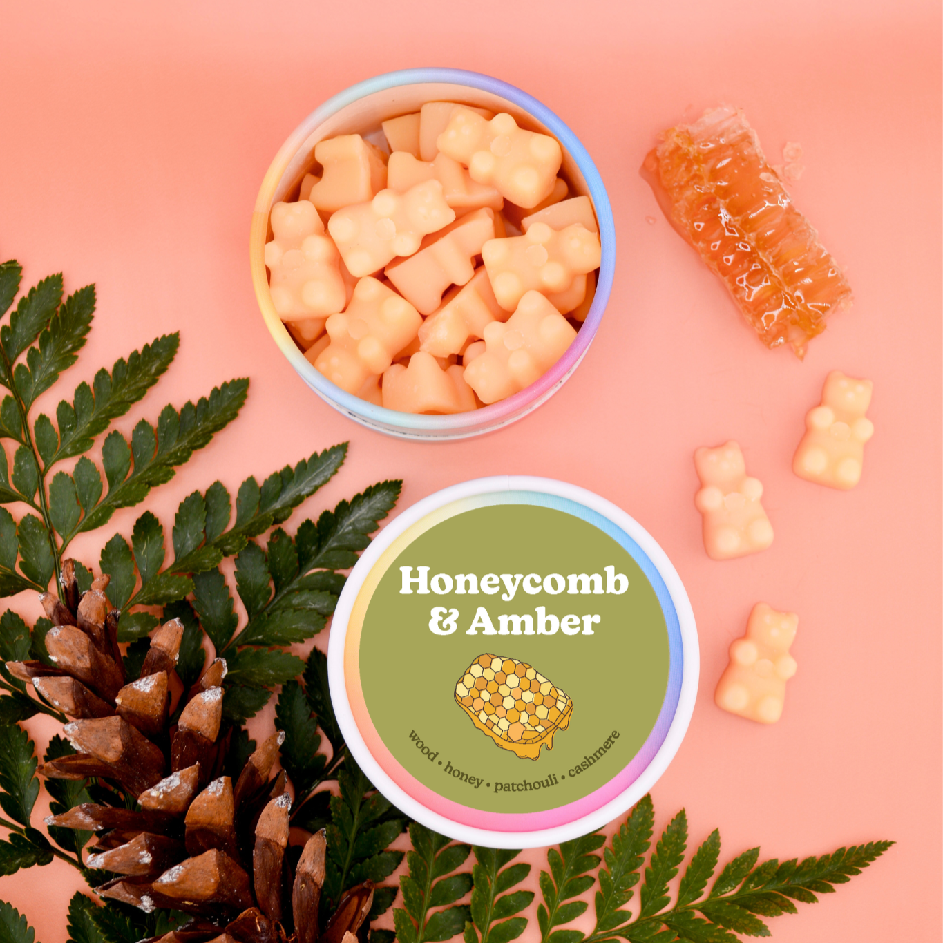 Blue and pink containers with peach-colored bear-shaped wax melts, featuring honeycomb and amber scent label, surrounded by g