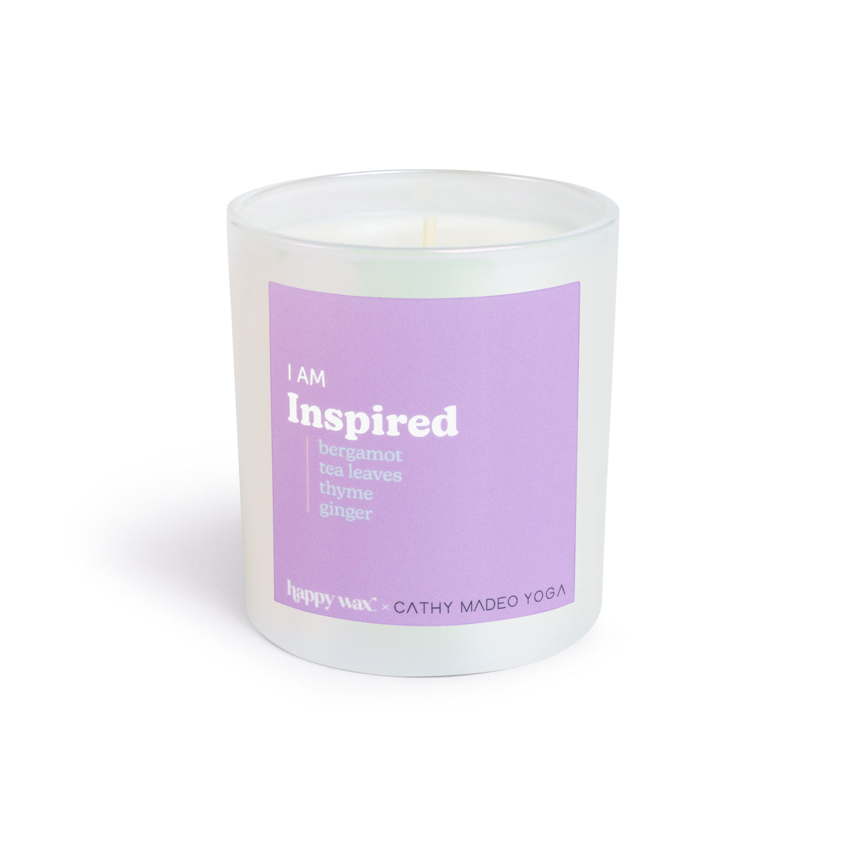 White cylindrical candle with purple label reading "I am Inspired" and scent notes including bergamot, tea leaves, thyme, and