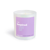 White cylindrical candle with purple label reading "I am Inspired" and scent notes including bergamot, tea leaves, thyme, and