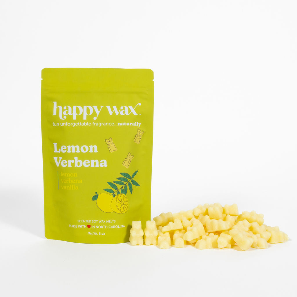 Yellow wax melts spilling from a lime green Happy Wax pouch labeled Lemon Verbena with lemon and leaf illustrations.