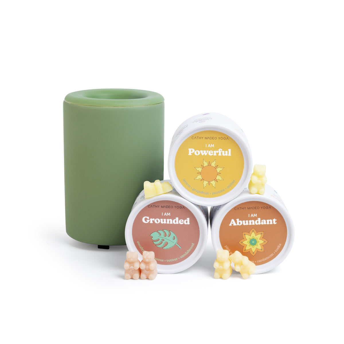 Green ceramic candle holder with three labeled wax melts in yellow, coral, and orange, plus wax melts scattered in front.