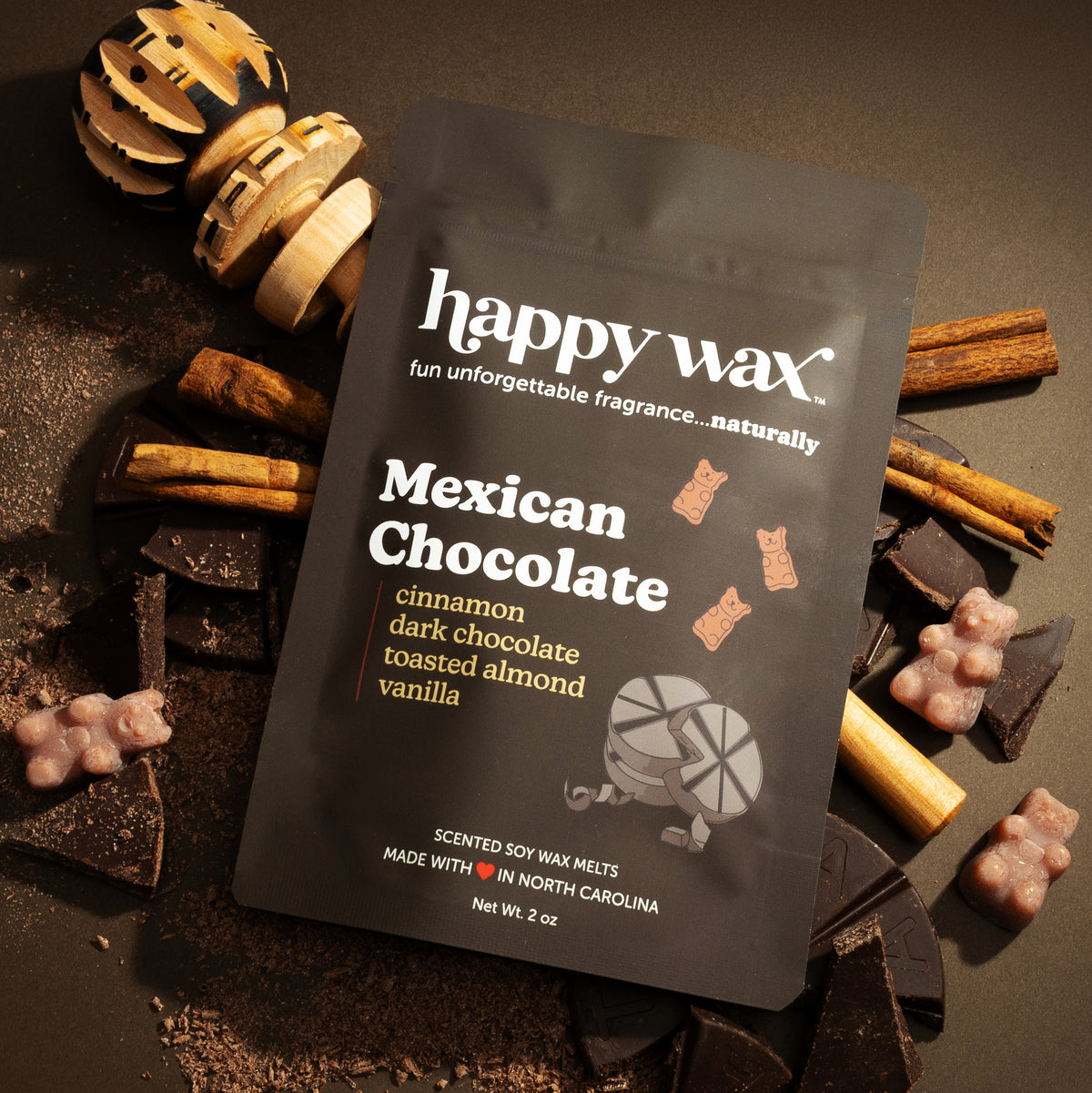 Black Happy Wax packaging for Mexican Chocolate scented soy wax melts surrounded by cinnamon sticks and dark chocolate pieces
