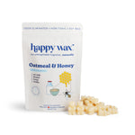 Cream-colored soy wax melts next to white pouch labeled "Happy Wax Oatmeal & Honey" with ingredient illustrations.