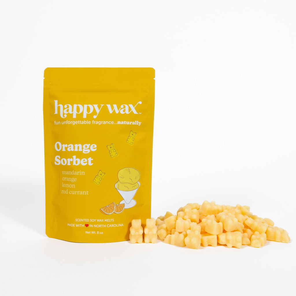 Yellow pouch of Happy Wax Orange Sorbet wax melts with pale yellow wax cubes scattered beside it.