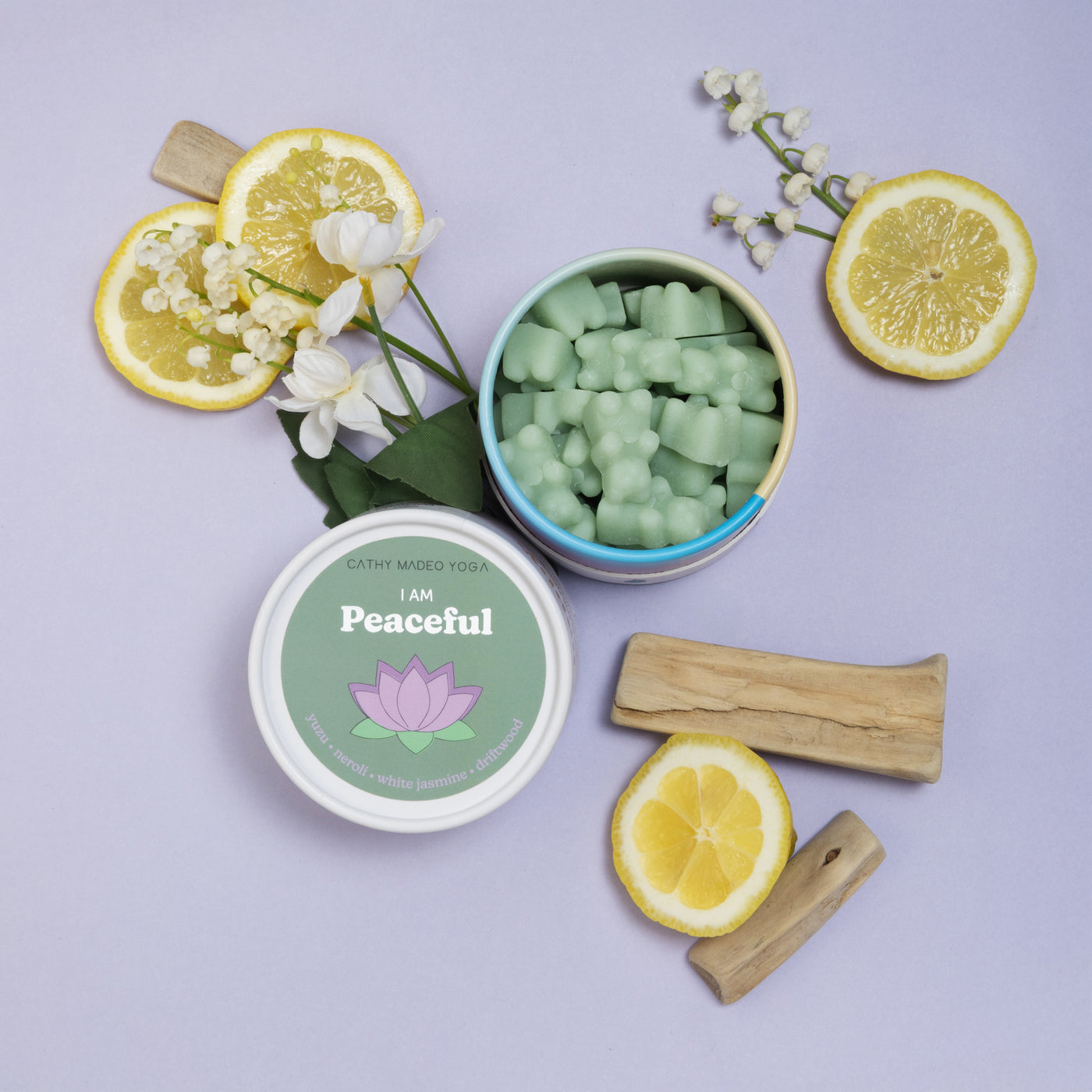 White container with green wax melts labeled "I am Peaceful" surrounded by lemon slices, white flowers, wooden sticks, and op