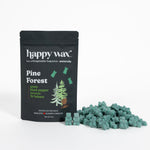 Black pouch of Happy Wax Pine Forest scented wax melts with green wax pieces displayed beside it.