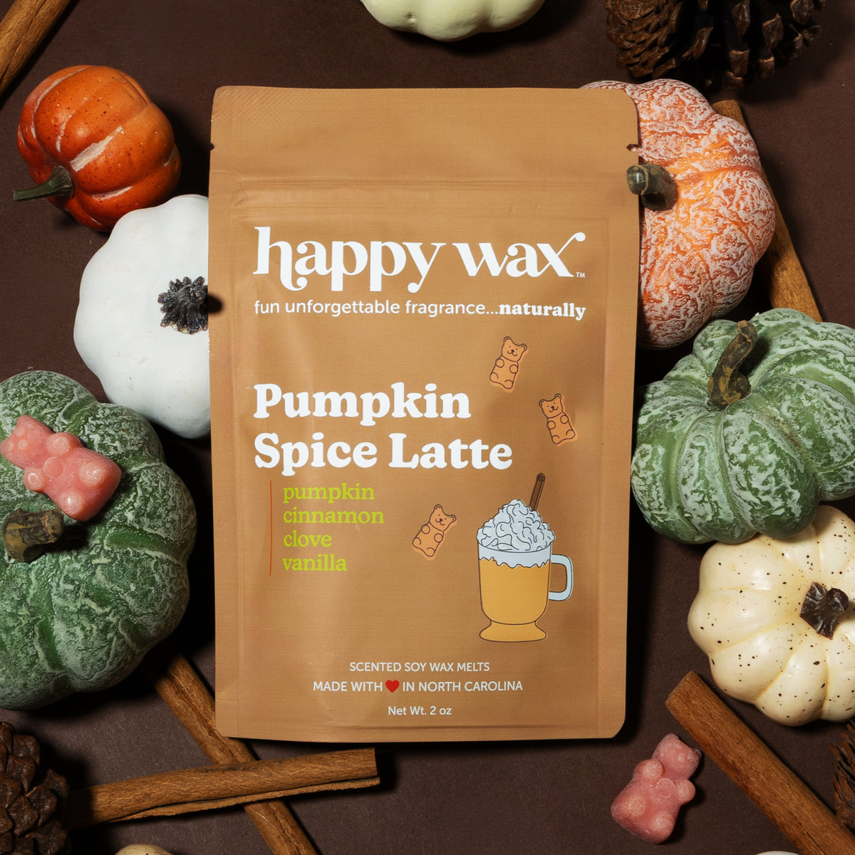 Tan Happy Wax packet of Pumpkin Spice Latte soy wax melts surrounded by decorative pumpkins and fall seasonings on wood surfa