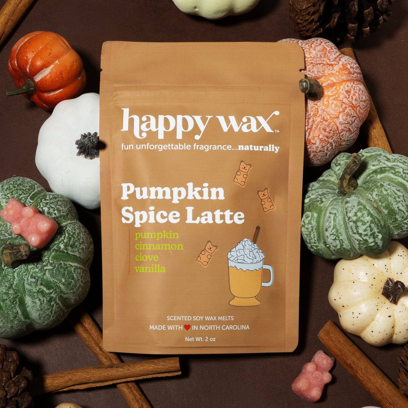 Tan Happy Wax packet of Pumpkin Spice Latte soy wax melts surrounded by decorative pumpkins and fall seasonings on wood surfa