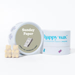 White ceramic container with "Sunday Paper" label and two cream-colored bear-shaped wax melts displayed beside happy wax bran