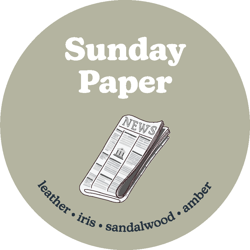Circular sage-green label with "Sunday Paper" text and illustration of a folded newspaper, listing leather, iris, sandalwood,