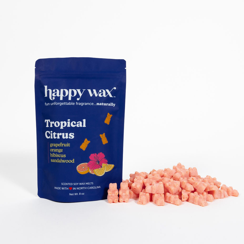 Navy blue pouch of Happy Wax Tropical Citrus wax melts with scattered pink wax cubes displayed beside it.