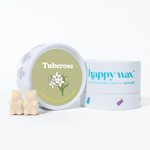 Cream-colored bear-shaped wax melts next to Happy Wax branded container with tuberose flower illustration on sage green label