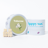 Cream-colored bear-shaped wax melts next to Happy Wax branded container with tuberose flower illustration on sage green label