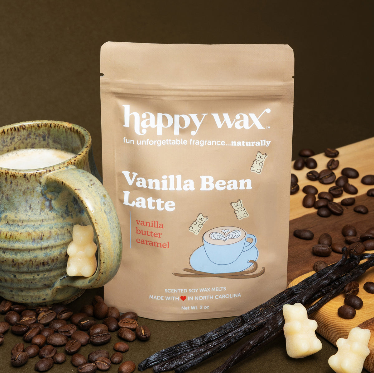 Vanilla Bean Latte wax melt package surrounded by coffee beans, vanilla pods, and cream-colored wax melts in a ceramic cup.