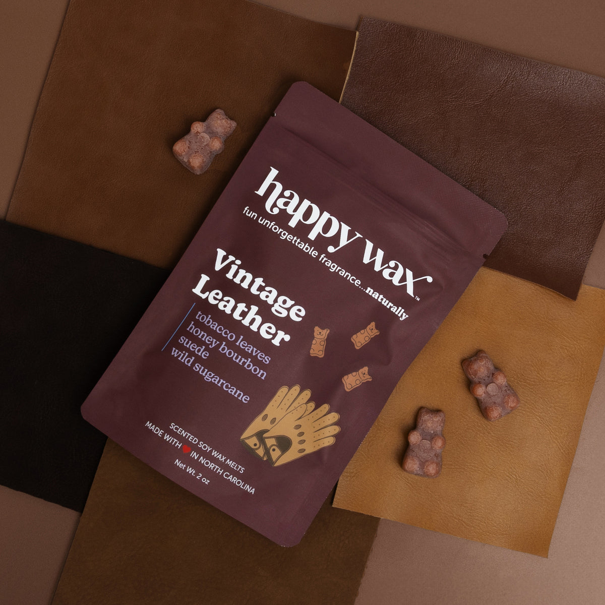 Happy Wax burgundy "Vintage Leather" wax melt package with bear-shaped melts on brown and tan fabric swatches.