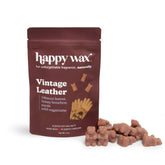 Brown pouch of Happy Wax Vintage Leather scented soy wax melts with tan wax pieces scattered beside it.