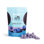 Light purple wax melts scattered next to blue and pink pouch labeled "Wake-Up Call" with blueberry graphics.