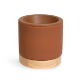 Cylindrical wax warmer with terracotta ceramic top and natural wood base.