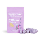 Purple pouch of Happy Wax Wildflower Meadow wax melts with scattered lavender-colored wax cubes beside it.