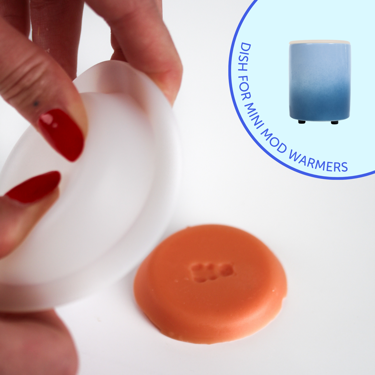 Hand holding white silicone dish above orange silicone dish with blue warmer shown in background.
