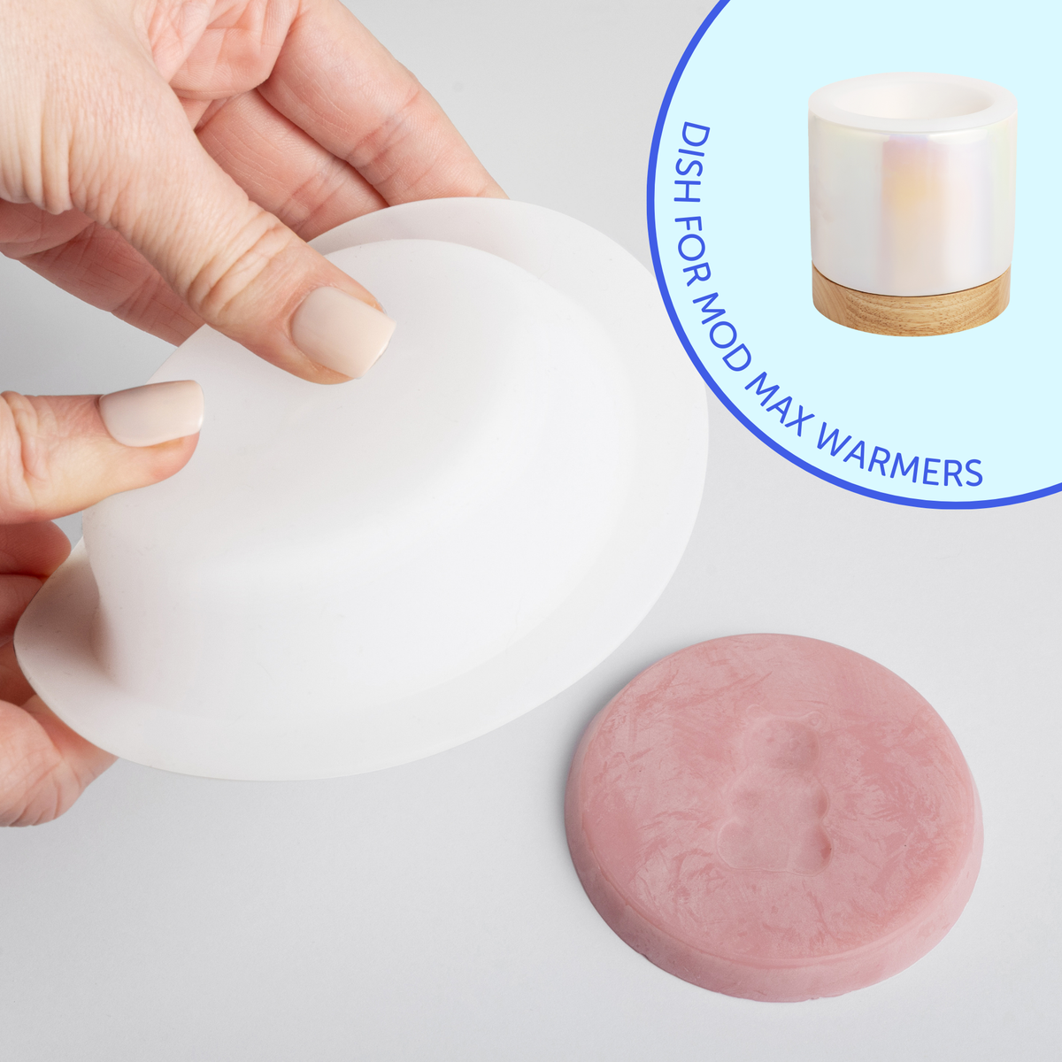 White silicone dish held in hand with pink wax melt below and ceramic warmer with cork band shown at right.