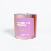 Pink cylindrical candle with purple label reading "Wildflower Meadow" and single lit wick.