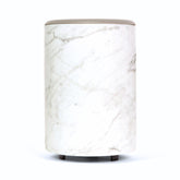 White marble-patterned cylindrical wax warmer with gray top and black feet.