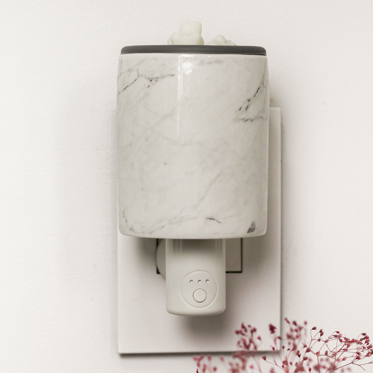 White marble-patterned outlet wax warmer with timer control and wax cubes on top.